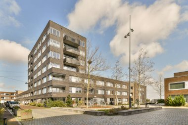 Şehrin ortasında bir apartman binası. Sokakta arabaları park edilmiş ve insanlar kaldırımdan aşağı yürüyor.