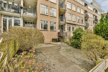 Binanın sağ tarafında ön tarafında bitkiler ve çalılar olan bir dış alan var.