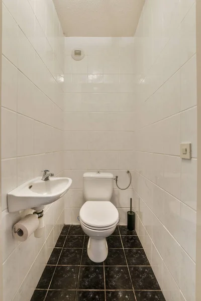 床に黒と白のタイルと小さなバスルーム 壁にシンクとトイレは大理石で作られています — ストック写真