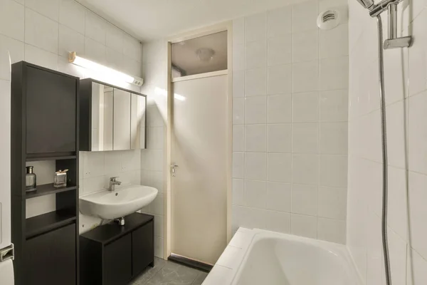シャワーストールの横の角に洗面台鏡と浴槽のあるバスルームは床に白いタイルで — ストック写真