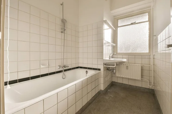 浴室は白で床に黒いタイルがあり浴槽の横にバスタブがあります — ストック写真