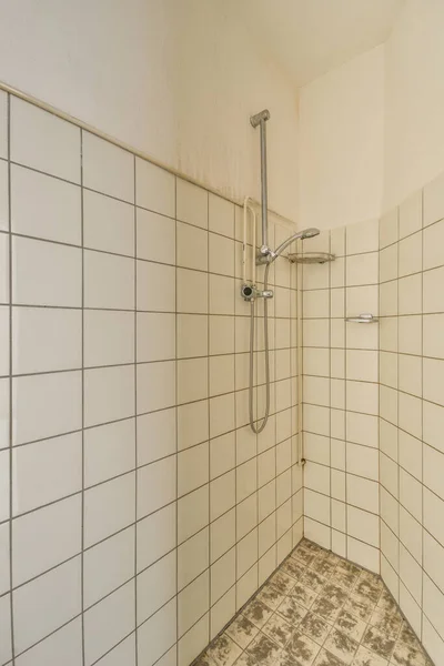 床にタイル張りのバスルームと壁に取り付けられたシャワーヘッド白いタイル張りの壁の前 — ストック写真