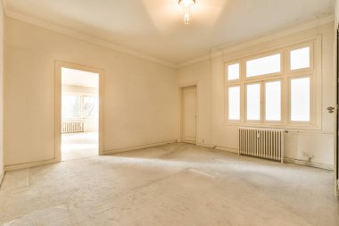 Pencereden içeri ışık giren boş bir oda ve yerde ya da kapıda duran kimse yok.