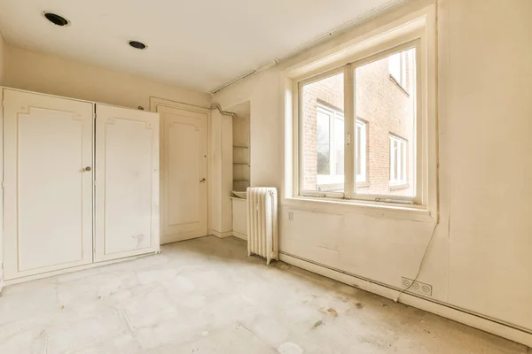 stock image an empty room with white cupboards and cabinets in the corner, looking out onto the street from the window