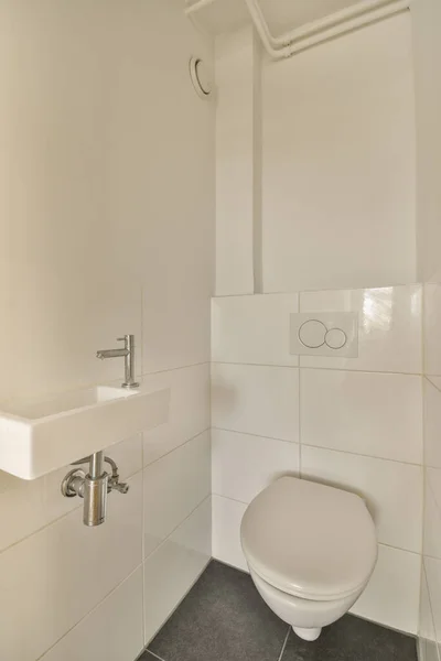 床にタイル張りの壁とタイル張りの小さな浴室に白いトイレがありその上に鏡があります — ストック写真