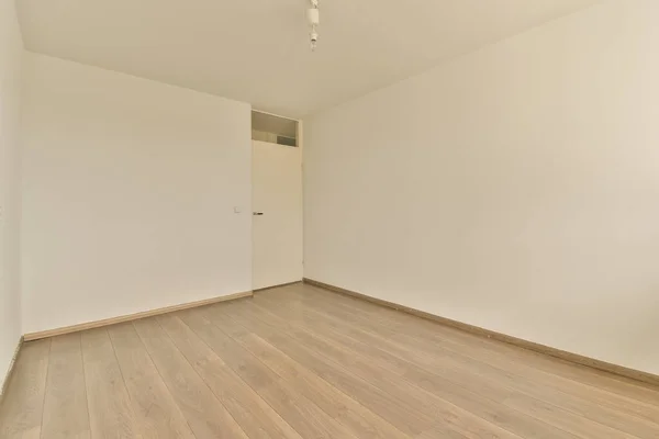 右边是一个有白色墙壁和木制地板的空房间 角落里有一个吊扇 — 图库照片