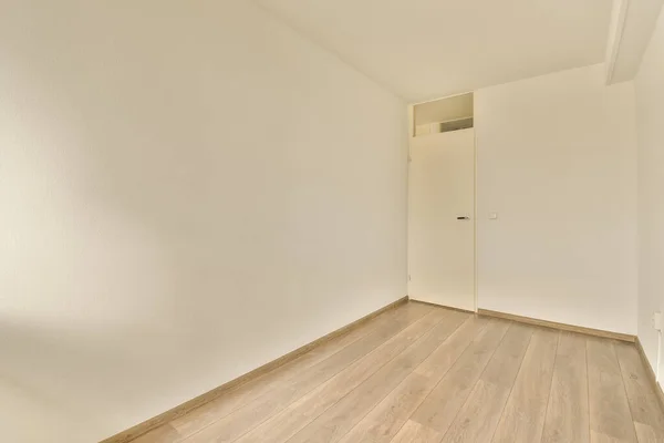 右边是一间空房间 墙壁是白色的 地板是木制的 左边的角落里有一扇门 — 图库照片