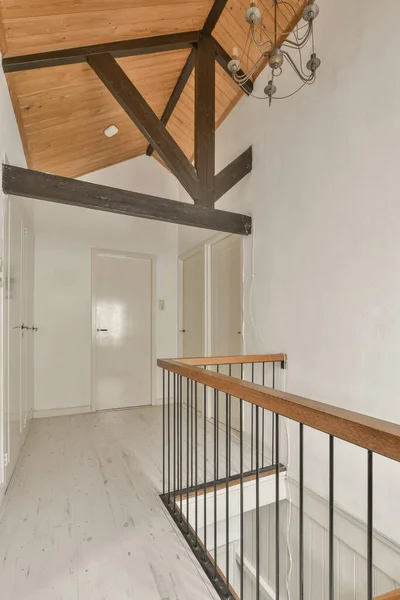 天花板上有一个有白色墙壁和木梁的空房间 有一个楼梯通往二楼 — 图库照片