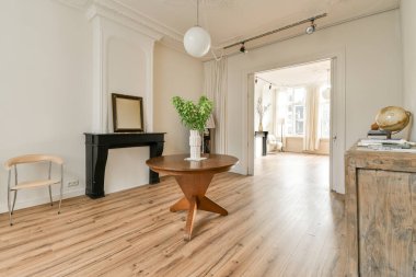 Duvarlarında ahşap döşeme ve beyaz süsleme olan bir oturma odası. Arka planda eski bir ahşap dolap var.