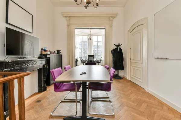 a dining room with purple chairs and a flat screen tv on the wall in the center of the room,