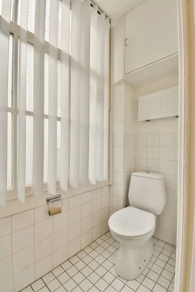 壁に窓がありタイル張りの床の下に白いトイレがあります — ストック写真