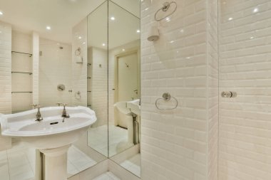 Yanındaki duvarda beyaz bir lavabo ve ayna olan bir banyo duş kabininde bir yürüyüş gibidir.