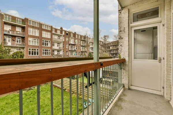 stock image a balcony with some buildings in the background and green grass growing on the ground next to the door is an open white door