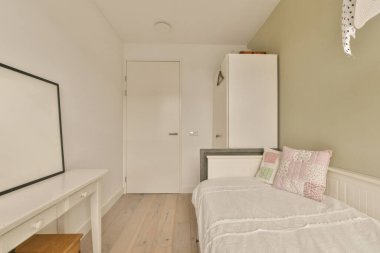 Yatak odası, şifonyer ve kapı yanındaki duvarda televizyon var.