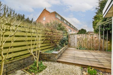 Arka bahçesinde ahşap çitler ve arka bahçesinde ağaçlar olan bir bahçe. Sağ tarafında elma ağacı da var.