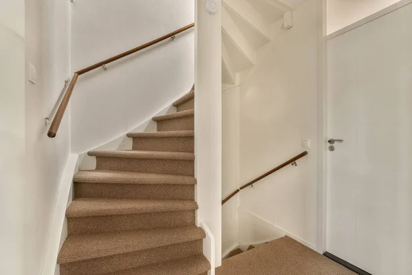 stock image a stairway way in a house with carpet on the floor and stairs leading up to the second floor, there is an open door