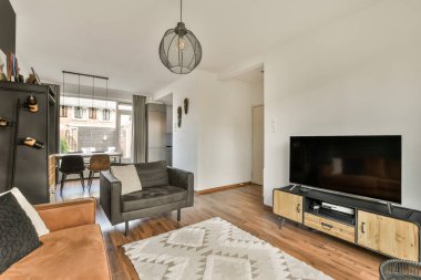 Kanepeleri olan bir oturma odası ve duvarında televizyon olan düz ekran televizyonun üzerine monte edilmiş bir televizyon.