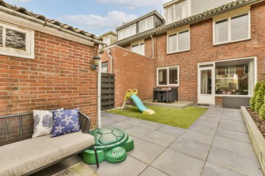 Arka bahçesinde bir bank, salıncak sandalyesi ve evin ön tarafında yeşil kaydırak var.