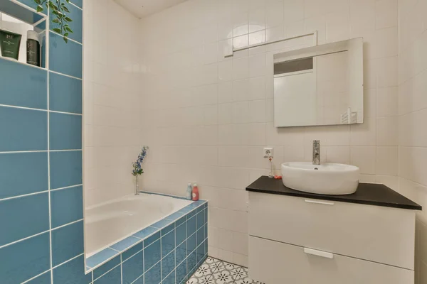 墙壁上有蓝白相间的瓷砖 浴缸角落里有水池和镜子 — 图库照片