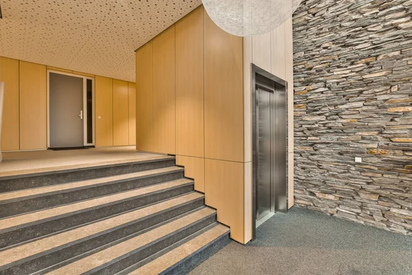 壁に石の壁と木のパネルがある建物の階段はエレベーターまで続く階段です — ストック写真