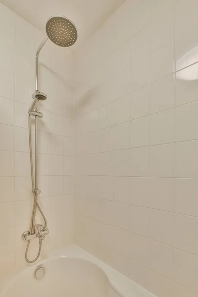 シャワーヘッドのある浴槽とパイプの端に手を置いて — ストック写真