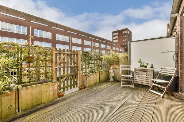 stock image an outside area with wooden decking and plants on the side of the building in the background is a blue sky filled with white