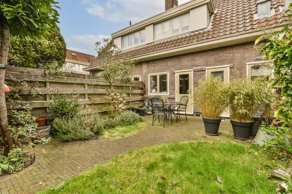 stock image a backyard area with some plants and pots on the ground, in front of a brick - built house