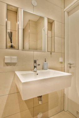 Lavabonun üzerinde beyaz lavabo ve ayna olan bir banyo önünde bir tuvalet görüntüsüdür.