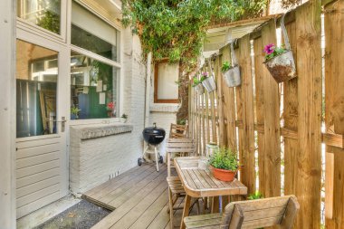 Evin dışında ahşap mobilyalar ve mangal için kullanılan bitkilerle dolu bir alan.