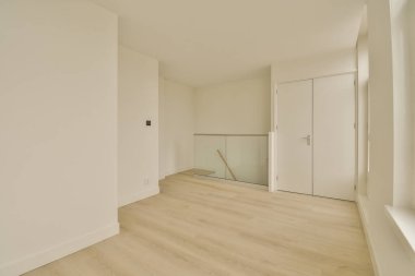 an empty room with white walls and wood flooring on the right, there is a mirror in the corner