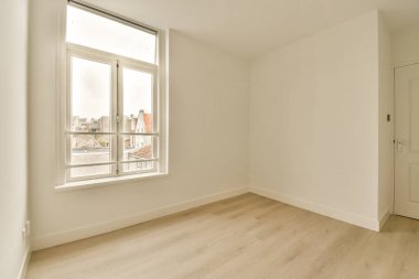 Ahşap zemini ve beyaz duvarları olan boş bir oda. Aşağıdaki şehre bakan bir pencere var.