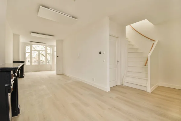 房间中央是一个有白色墙壁和木制地板的空房间 是通往二楼的楼梯 — 图库照片