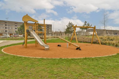 Parkın ortasında salıncaklı, slaytlı ve slaytlı bir oyun alanı var.