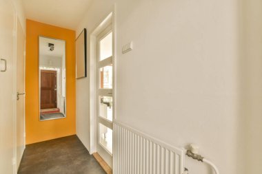 Turuncu duvarlı bir koridor ve parlak turuncuya boyanmış beyaz bir süsleme.