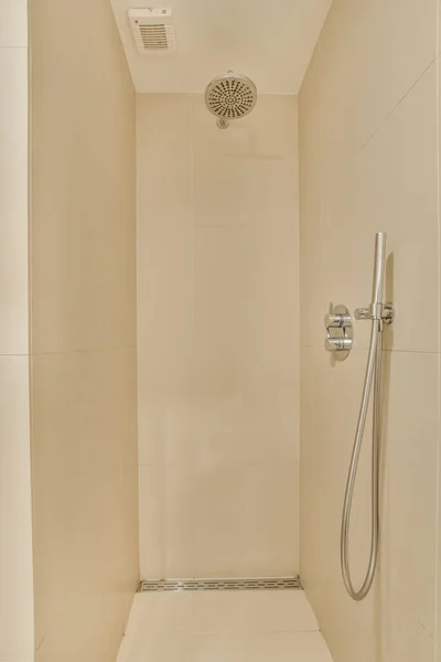 シャワー室にはシャワーヘッドと手があり床には白いタイルがあります — ストック写真