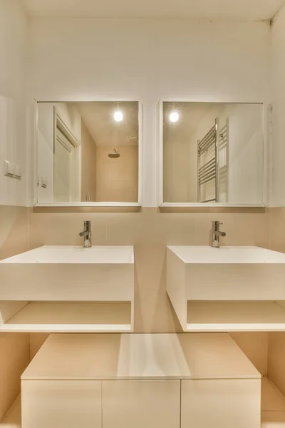 壁に鏡のある浴室に2つのシンクがあり1つのシンクは空ですが光はありません — ストック写真