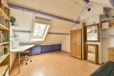 Raflarda kitaplar ve odanın önünde bir kanepe olan bir oda mobilyayla dolu.