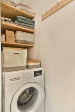 Köşesinde çamaşır makinesi ve kurutma makinesi olan bir çamaşır odası, ayrıca çamaşır deposu olarak da kullanılıyor.