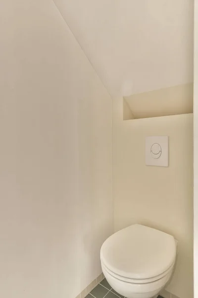 房间角落有一个厕所 墙上有白色的墙 地板上有绿色的瓷砖 有一个电源插座 — 图库照片