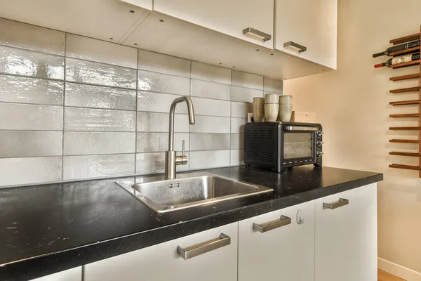 Eine Küche Mit Schwarzen Arbeitsplatten Und Weißen Schränken Der Ecke — Stockfoto
