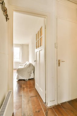 Ahşap döşemeli ve beyaz duvarlı bir oda. Odanın sağ tarafında klima var.