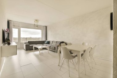 Beyaz döşemeli bir oturma odası ve açık planlı yemek odası çok modern.