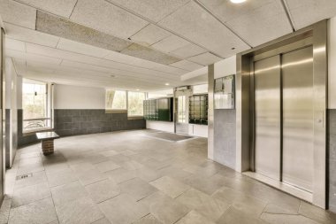 Orta ve ikinci katlarda iki asansörü olan boş bir bina. Kapısı ya da penceresi yok.