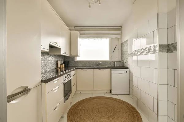 Uma Pequena Cozinha Com Armários Brancos Bancadas Pretas Chão Nesta — Fotografia de Stock