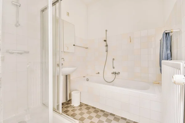 有瓷砖地板和白色墙壁的浴室 包括右边角落里的浴缸 是一个淋浴间 — 图库照片