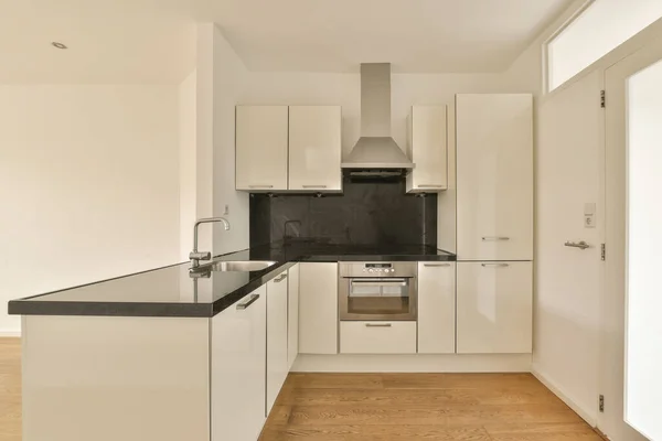 Een Keukenhoek Met Witte Kasten Zwarte Aanrechtbladen Vloer Voor Deur — Stockfoto