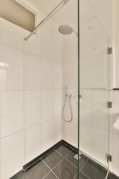 床に黒と白のタイルが敷かれたモダンなバスルーム ガラスシャワー ストール ドアとトイレが角にあり — ストック写真