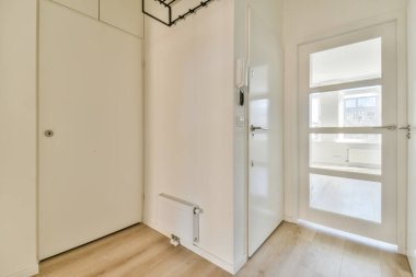 Ahşap zemini ve beyaz duvarları olan boş bir oda. Köşedeki pencereye açılan bir kapı var.