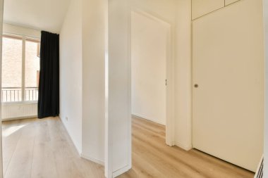 an empty room with wooden floors and white walls, there is a large mirror on the wall to the right