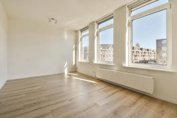 an empty room with hardwood flooring and large windows overlooking the cityscarings in this photo is taken from inside